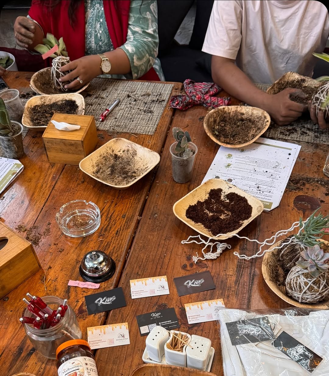 Hands shaping a moss ball with soil during a kokedama making workshop